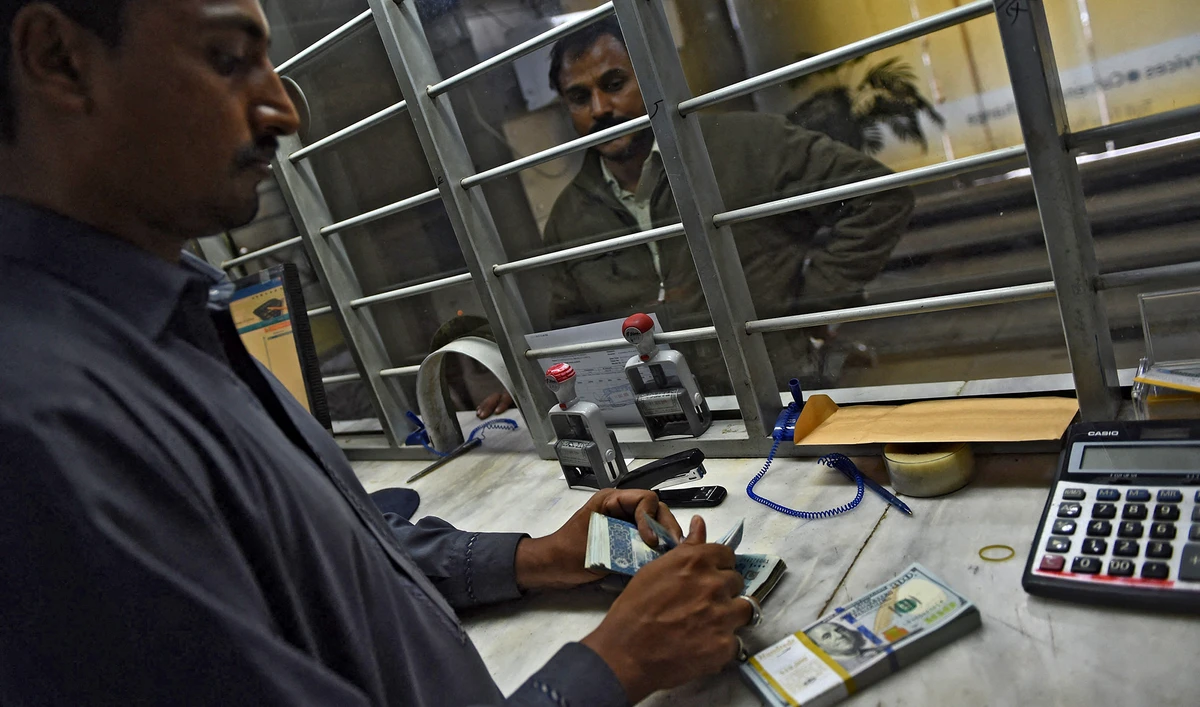A Pakistani currency dealer counts rupees and US dollars at a currency exchange in Karachi, Pakistan, on December 17, 2015. (AFP/File)
