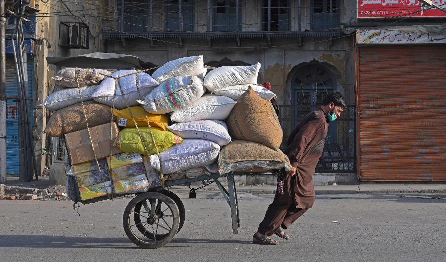 A labourer pulls a handcart laden with sacks of food at a market in Lahore on April 10, 2021. (AFP)