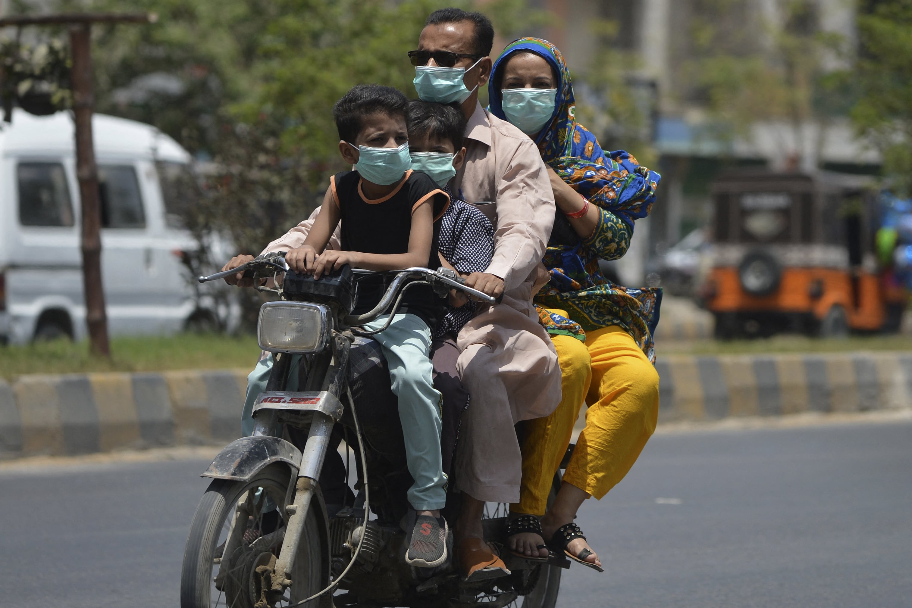 A family wearing face masks as a safety protocol against the Covid-19 coronavirus ride a motorbike along a street in Karachi on April 27, 2021. (AFP photo)