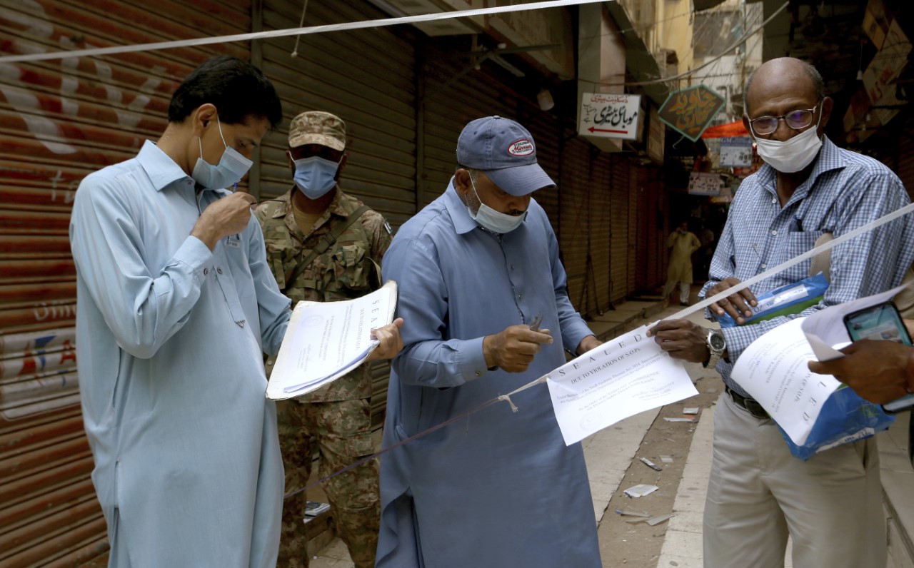 Officials gather to seal a market on the violation of new restrictions announced by government to control the spread of the coronavirus, in Karachi, Pakistan, Saturday, May 1, 2021. (AP)
