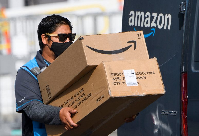 (FILES) In this file photo taken on February 02, 2021, an Amazon delivery driver carries boxes into a van outside of a distribution facility in Hawthorne, California. (AFP)