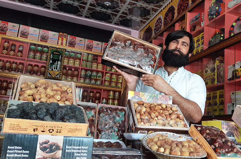 Hussain Baksh poses with boxes of dates at his shop in Khairpur’s Thehri area in Pakistan's Sindh province on May 01, 2021. (AN photo by Zulfiqar Kunbhar)