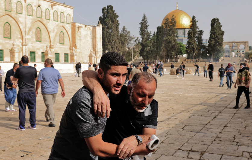 A Palestinianman helps a wounded fellow protester amid clashes with Israeli security forces at Jerusalem's Al-Aqsa mosque compound on May 10, 2021.(AFP)
