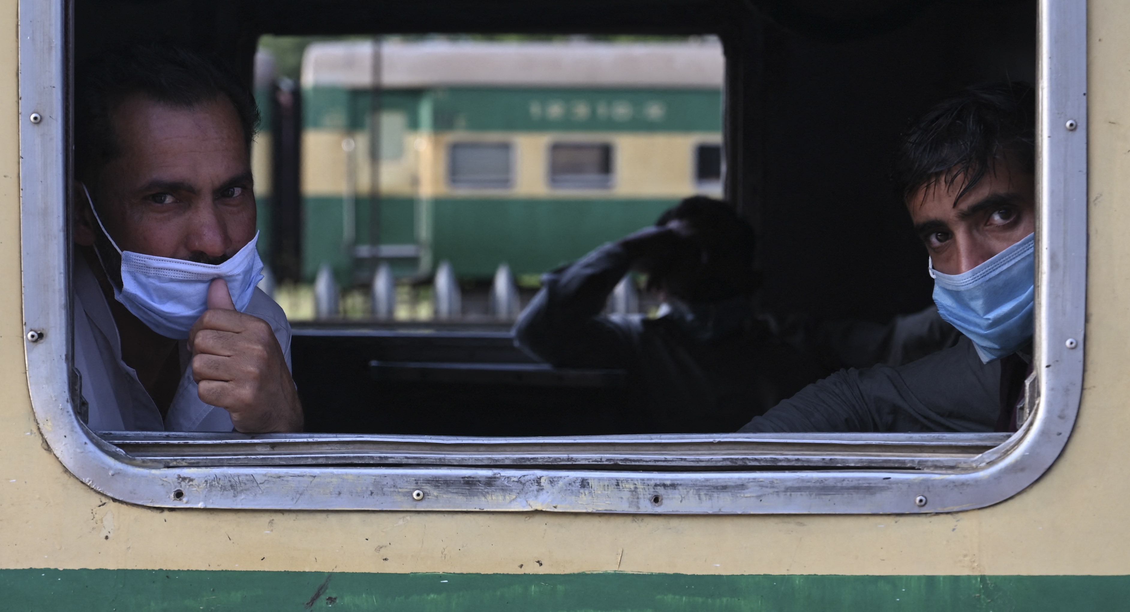 Passengers wearing facemasks look out from a window of a train as they are going to their hometown during a nine-day shutdown in a bid to prevent a surge in Covid-19 cases on the Muslim holiday of Eid al-Fitr, in Rawalpindi on May 11, 2021. (AFP)
