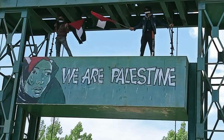A graffiti painted by a Kashmiri artist in Srinagar, Indian adminsterred Kahsmir, shows a woman wearing a scarf made of a Palestinian flag and a tear tricking from her eye, with the words: "WE ARE PALESTINE". The graffiti was later painted over by Indian police May 15, 2021. (Source: Twitter)