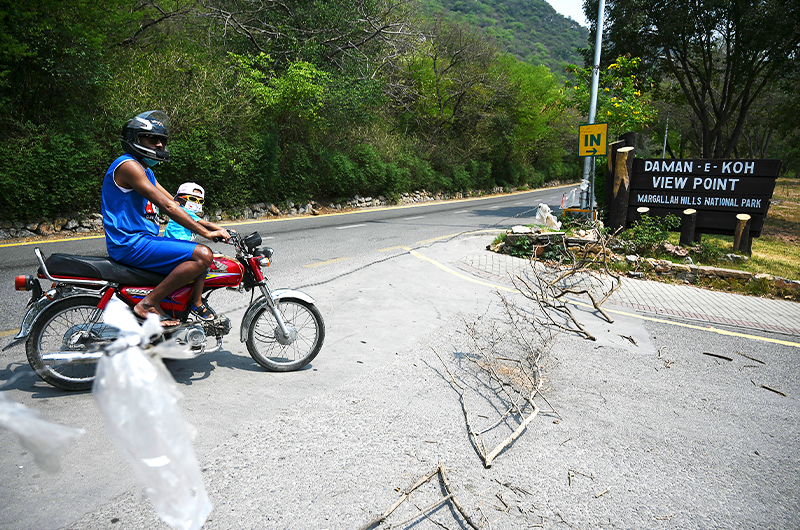 A motorcyclist stops at the closed main entrance of the Damn-e-Koh viewing point in Islamabad, Pakistan, on May 10, 2021. (AFP)