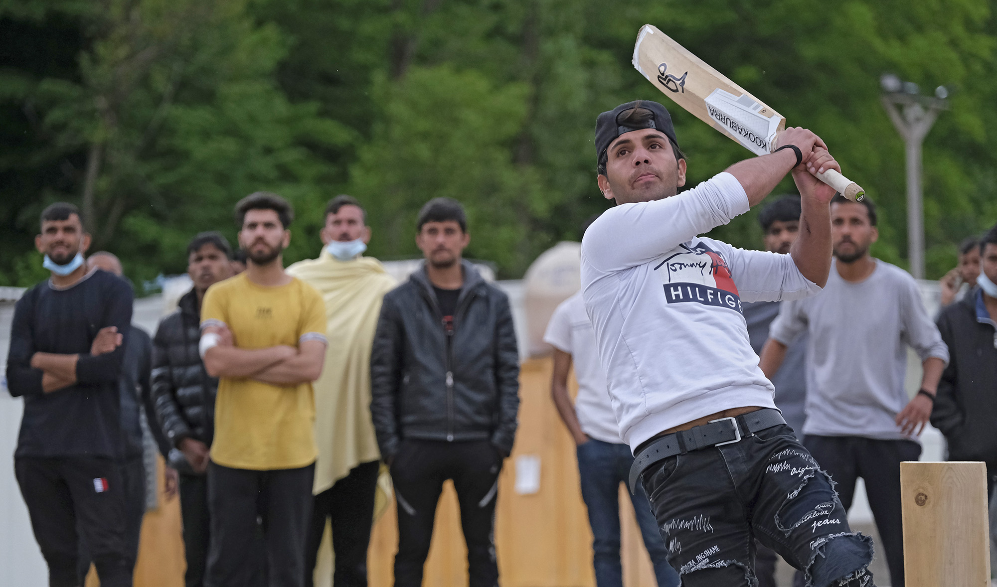 A batter hits the ball as migrants play a game of cricket in Blazuj migrant camp in Bosnia's capital of Sarajevo on May 19, 2021. (AP)