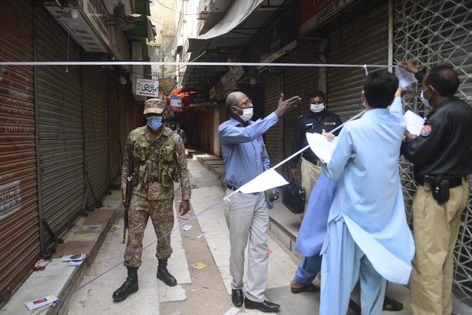 Local government staff and policemen display notices after closing a market area for not following Covid-19 coronavirus restrictions to limit the spread of the Covid-19 coronavirus, in Karachi on May 1, 2021. (AFP)