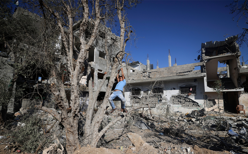 A Palestinian boy plays on May 24, 2021 next to buildings damaged damaged by Israeli air strikes in Gaza. (AFP)