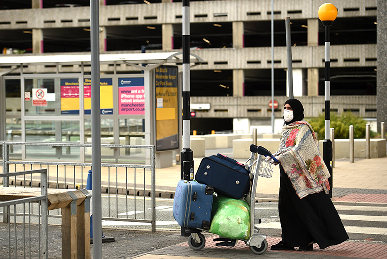 A passenger wearing PPE (personal protective equipment), including a face mask as a precautionary measure against COVID-19, pushes his luggage after at Manchester Airport in northern England, on June 8, 2020. (AFP)