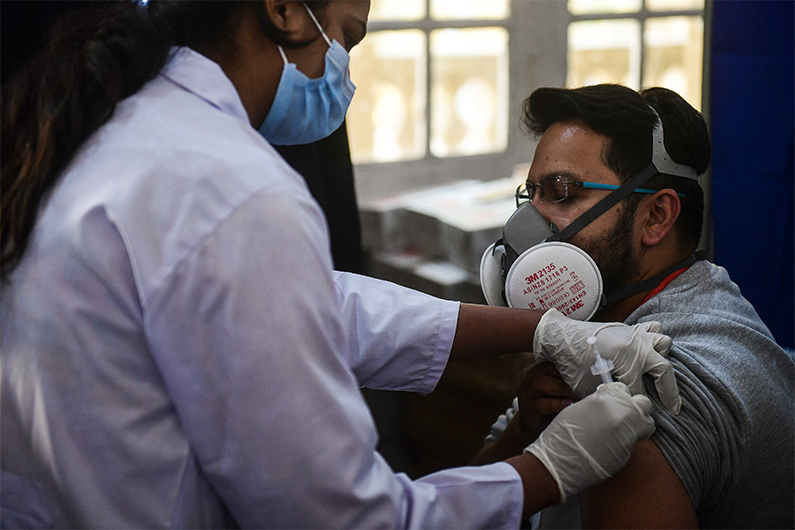 A health worker (R) receives a dose of the Chinese-made Sinopharm Covid-19 vaccine, at a vaccination centre in Karachi on February 3, 2021. (AFP)