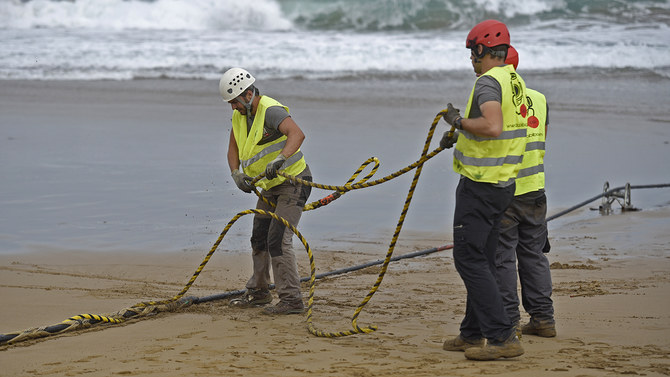 In this file photo, operators handle an undersea fiber optic cable at Arrietara beach near the Spanish Basque village of Sopelana on June 13, 2017. (AFP)