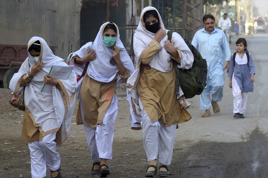 Students wearing facemasks walk through a street to their school in Peshawar on September 15, 2020. (AFP/File)