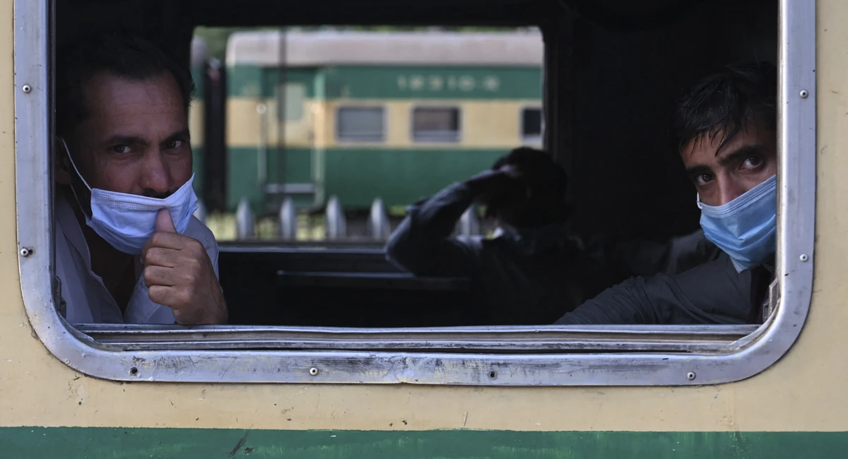 Passengers wearing facemasks look out from a window of a train as they are going to their hometown during a nine-day shutdown in a bid to prevent a surge in Covid-19 cases on the Muslim holiday of Eid al-Fitr, in Rawalpindi on May 11, 2021. (AFP)
