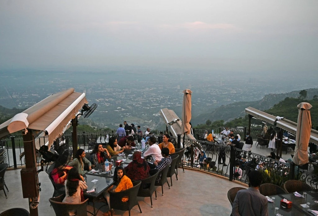 People wait for food on top of a restaurant on Margalla Hills in Islamabad on August 10, 2020, after government announced it would be lifting most of the country's remaining coronavirus restrictions after seeing new cases drop for several weeks. (AFP/File)