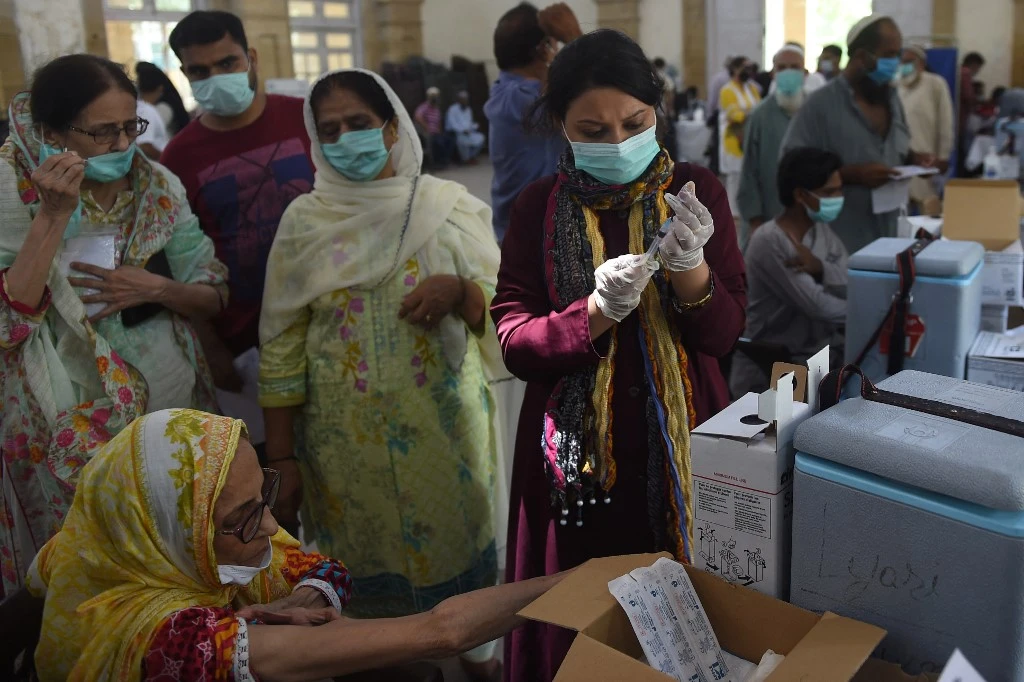 A health worker prepares to inoculate a woman with a dose of the Sinopharm vaccine at a vaccination center in Karachi on May 23, 2021. (AFP)