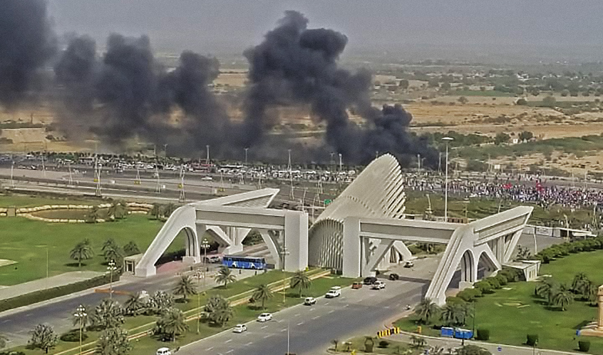 Smoke billowing outside the main entrance of the Bahria Town neighborhood in Karachi, Sindh province on June 6, 2021 amid protests by indigenous Sindhi groups against alleged land grabbing. (Photo courtesy: social media)