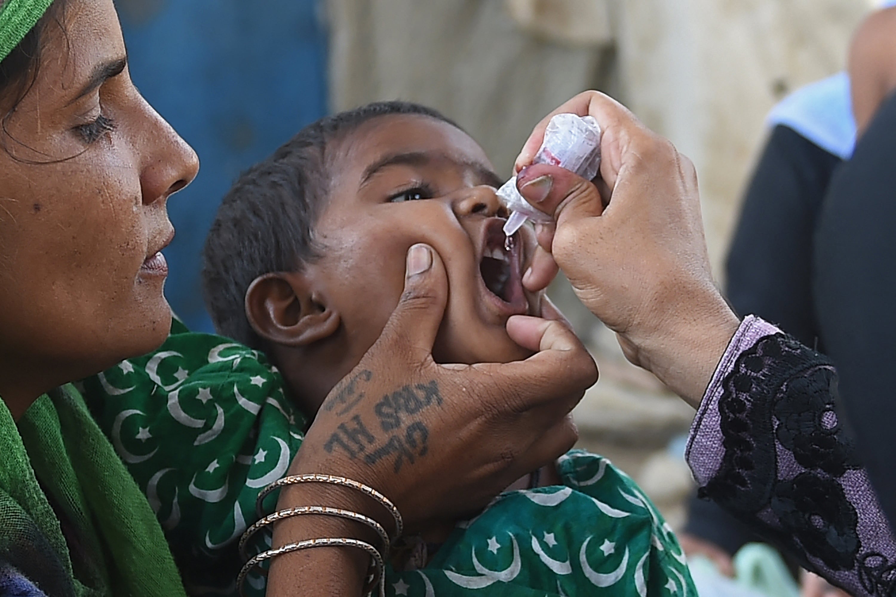 A health worker administers polio vaccine drops to a child during a polio vaccination campaign at a slum area in Karachi on June 7, 2021. (AFP)