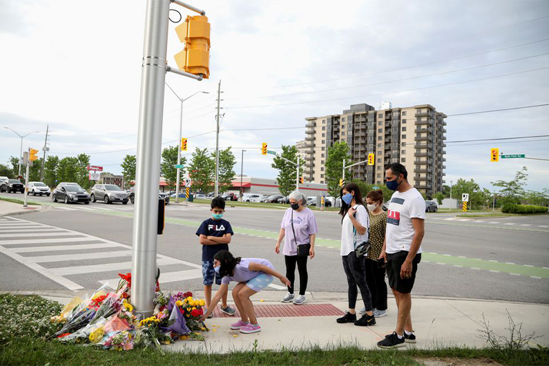 People lay flowers at the fatal crime scene where a man driving a pickup truck jumped the curb and ran over a Muslim family in what police say was a deliberately targeted anti-Islamic hate crime, in London, Ontario, Canada June 7, 2021. (REUTERS)