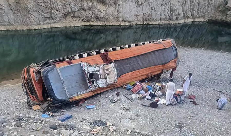 Locals gather supplies next to a damage bus at the site of accident in Khuzdar, a remote district in the Pakistan's southwestern Balochistan province, Friday, June 11, 2021. (AP)