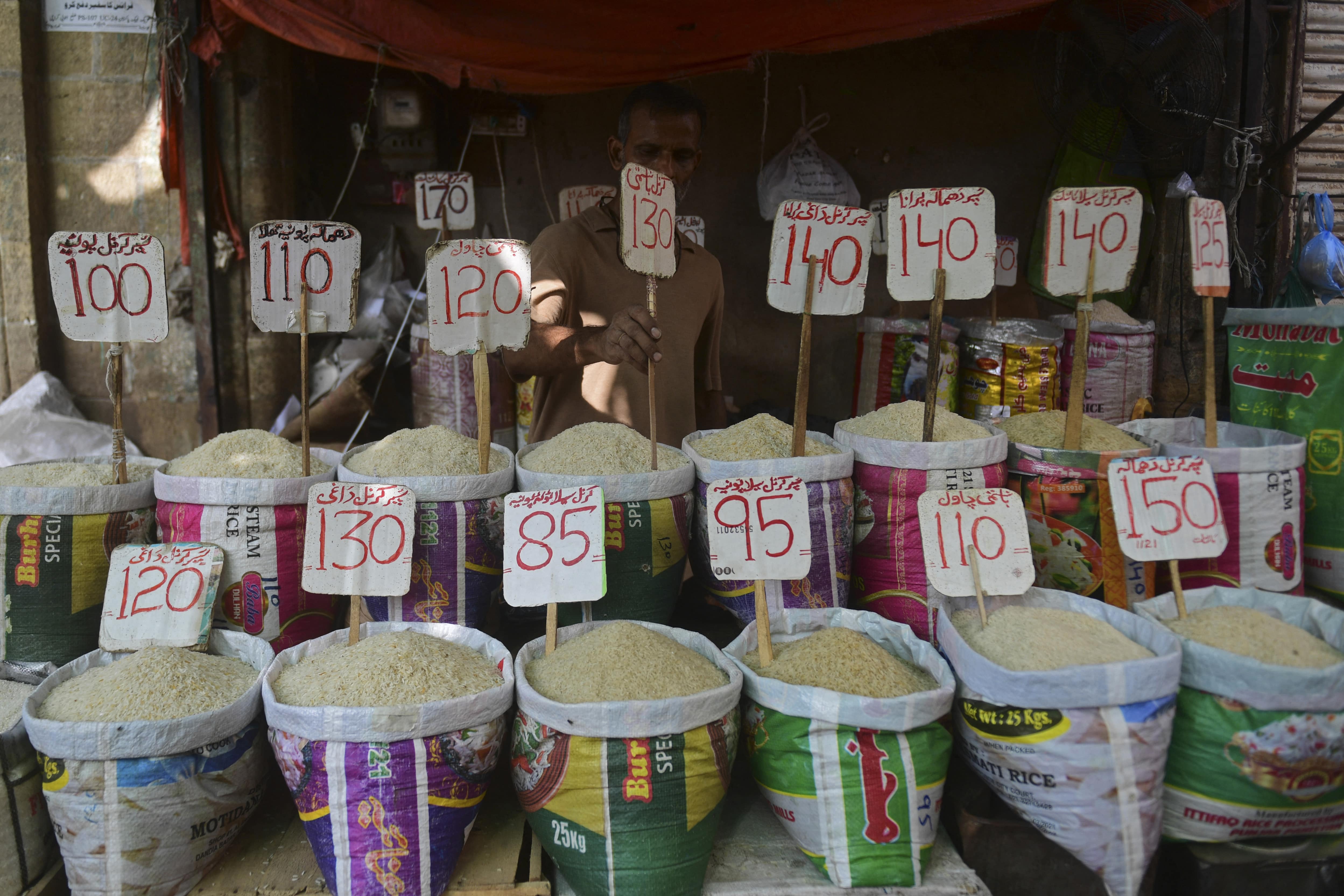A shopkeeper fixes the price tag of rice at his shop in a market in Karachi on June 10, 2021. (AFP)