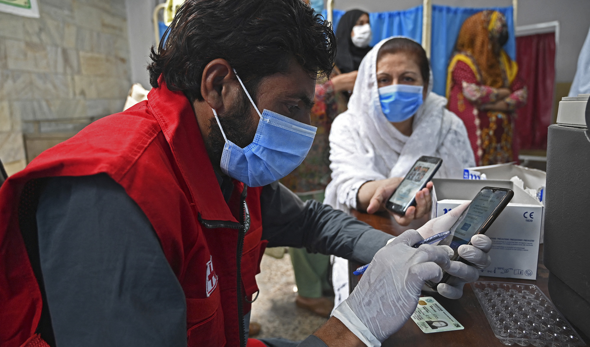 A health worker tracks the Covid-19 coronavirus vaccine registration code of a woman on his phone at the Red Crescent vaccination centre in Rawalpindi on May 24, 2021. (AFP/File)