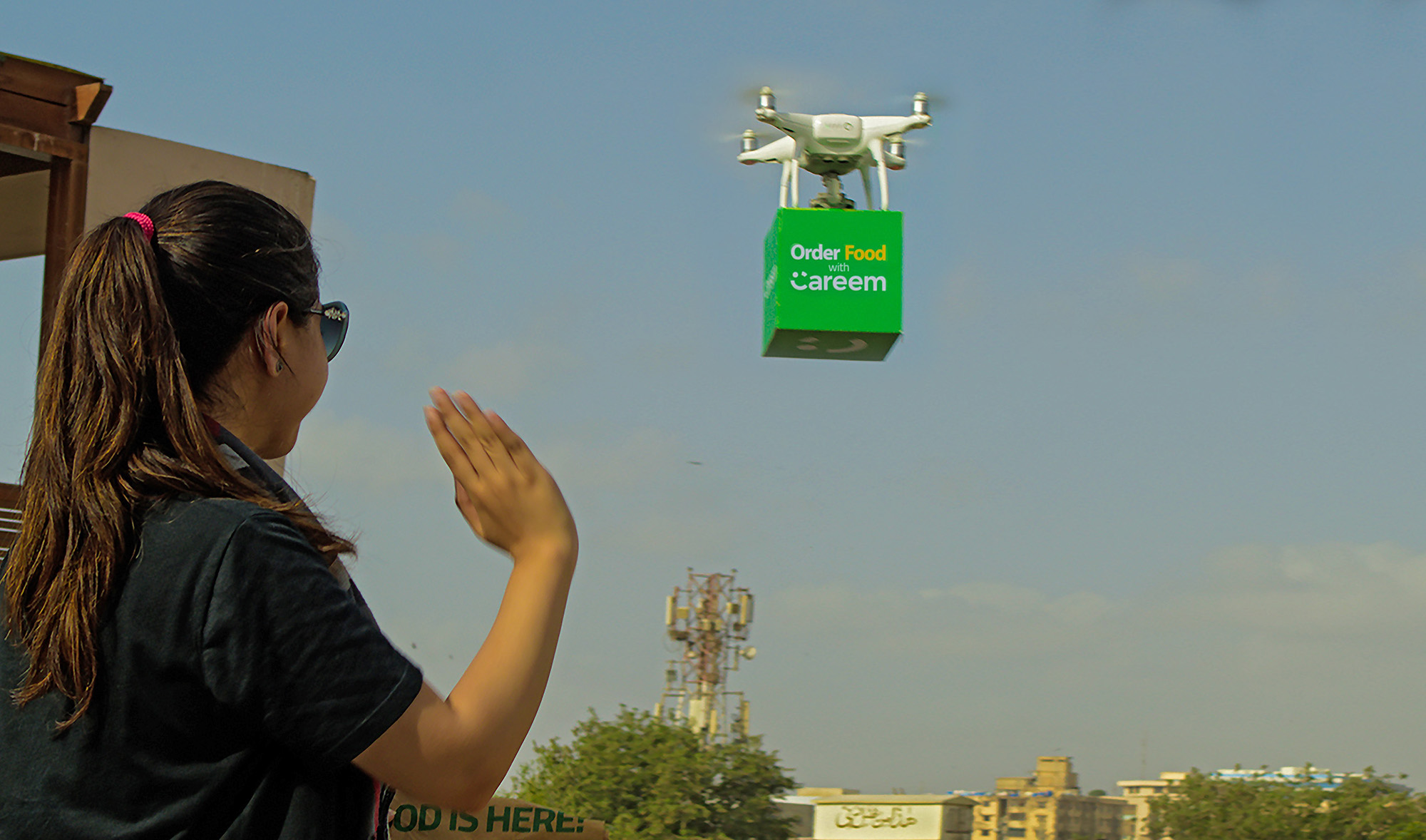 In this undated photo, a jubilant customer waves at a drone after receiving her order through Careem’s newly launched food delivery drone service. (Photo courtesy: @CareemPAK/Twitter)