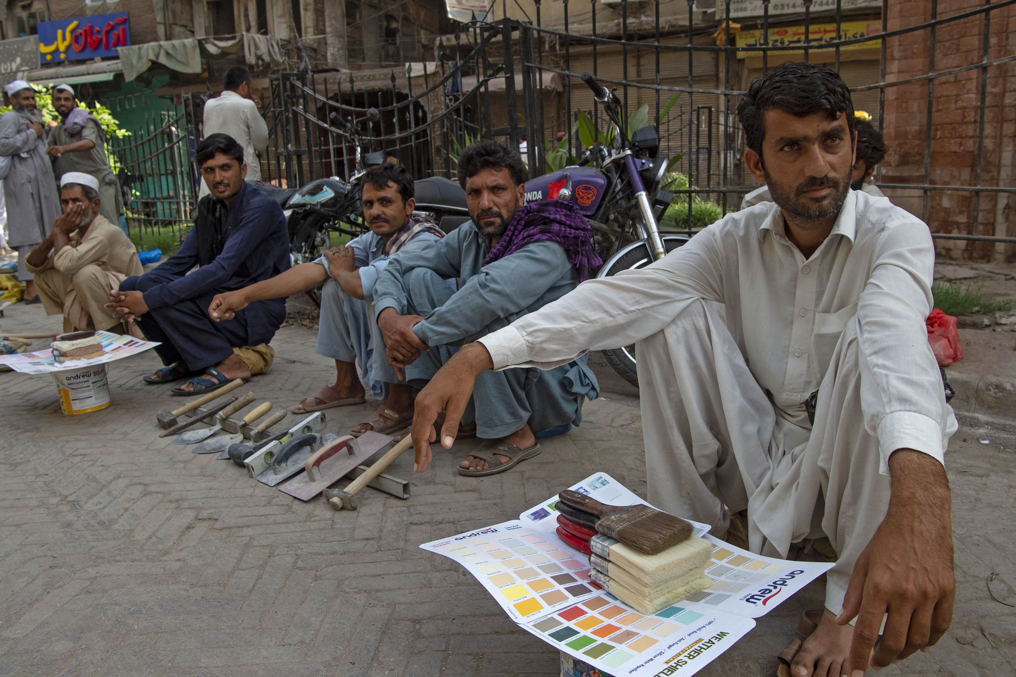 Daily wage labourers sit along the roadside as they wait to be hired for work a day after the Pakistan government announced the annal fiscal budget in Peshawar on June 12, 2021. (AFP)