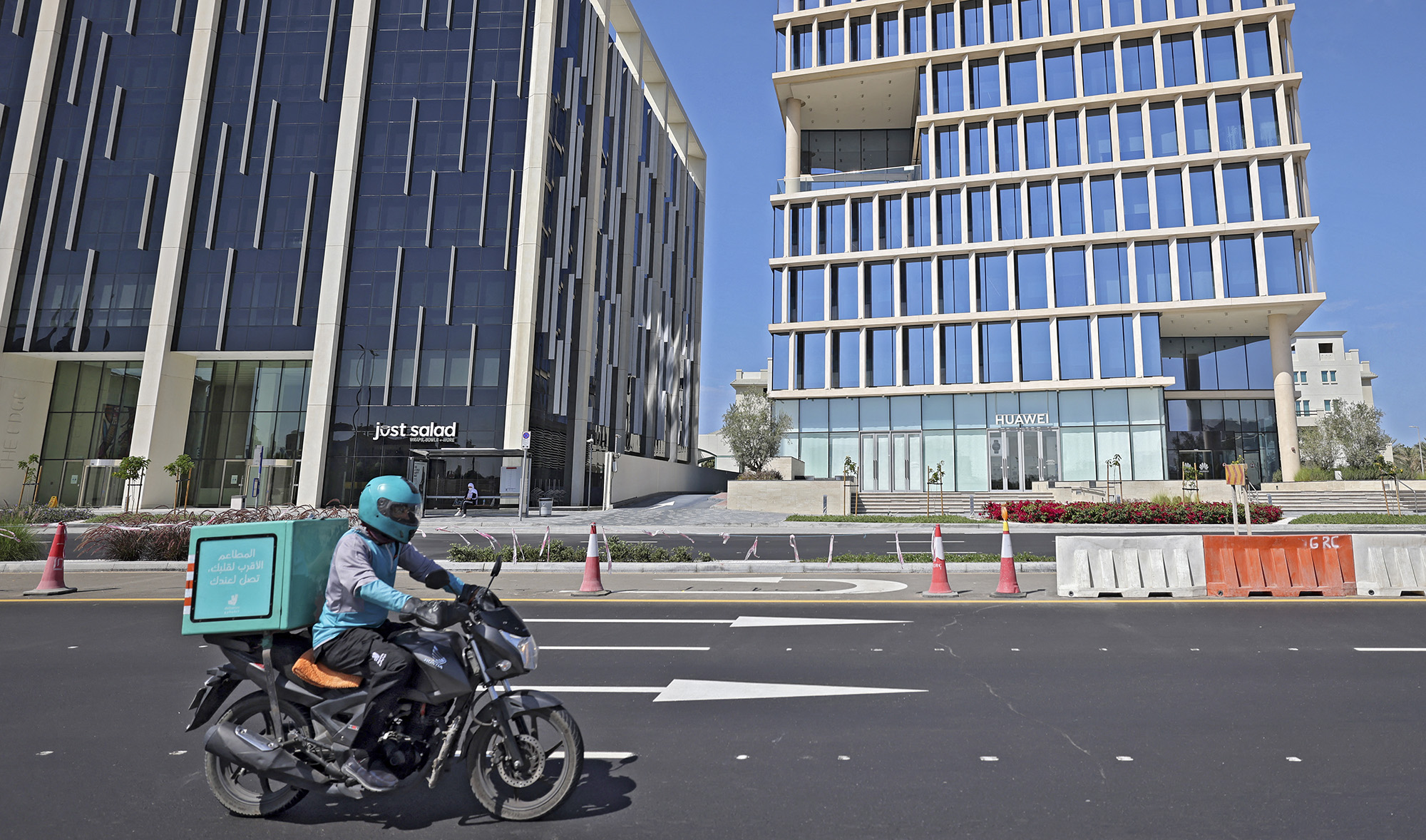 A delivery person rides a motorcycle along a road past the Huawei Building in Dubai, UAE, on February 22, 2021. (AFP)