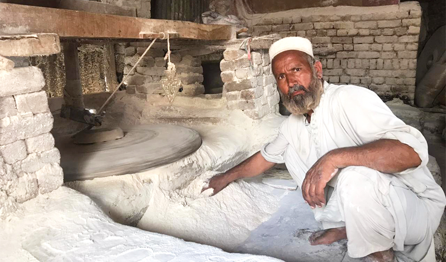 A man grinds wheat at a traditional watermill in Jranda Kali, on the outskirts of Peshawar, Pakistan, on June 11, 2021. (AN Photo)