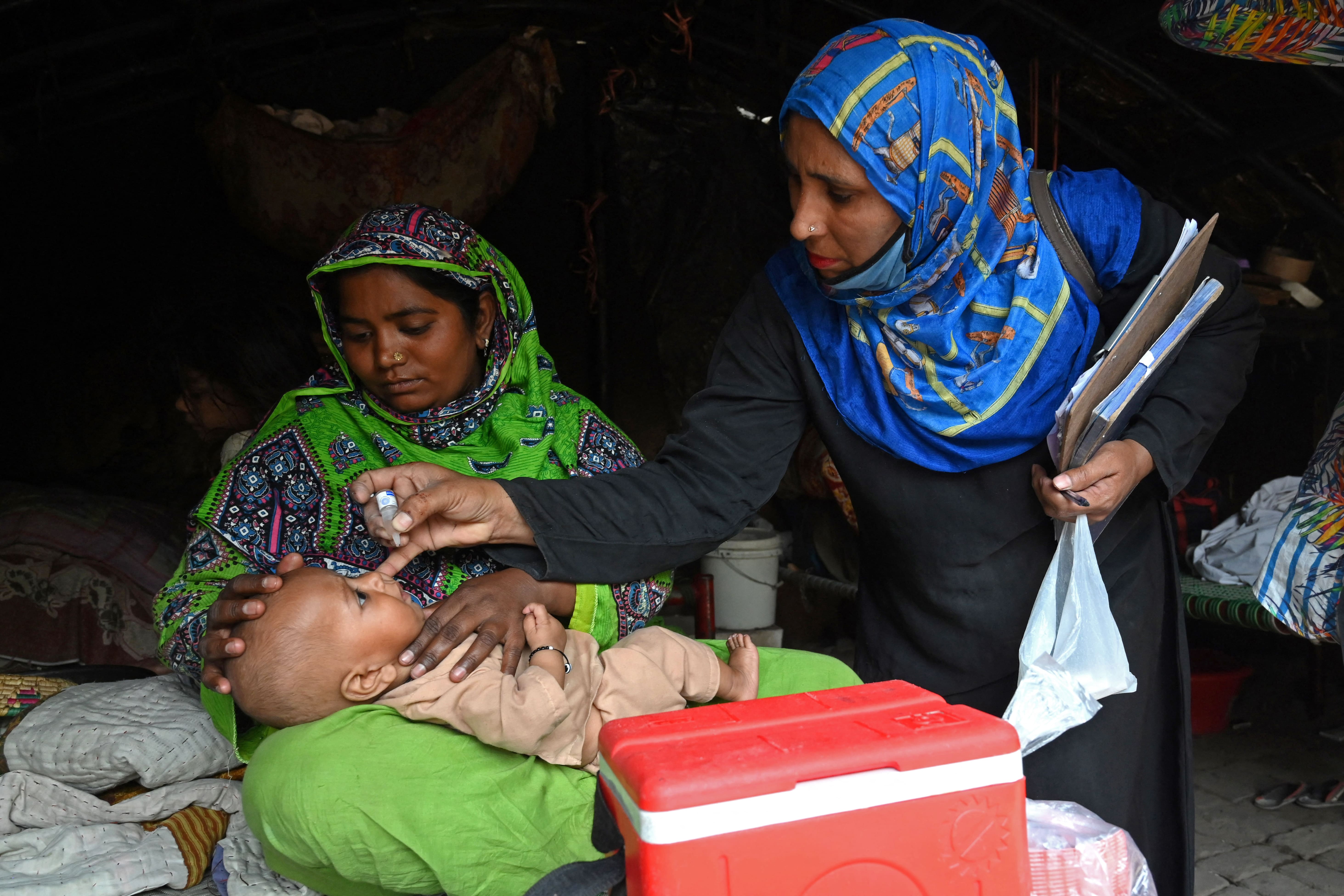 A health worker administers polio vaccine drops to a child during a polio vaccination door-to-door campaign at a slum area in Lahore on March 29, 2021. (AFP)