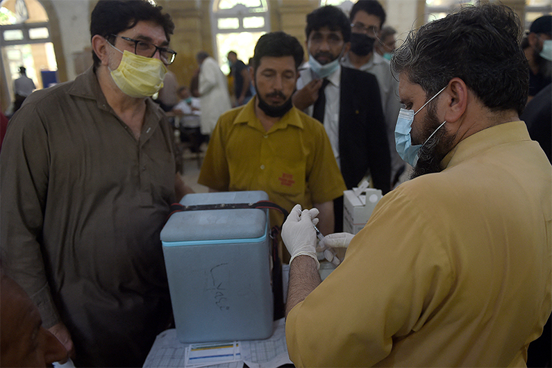 A health worker prepares to inoculate a man with a dose of the Sinopharm Covid-19 coronavirus at a vaccination centre in Karachi on May 26, 2021. (AFP)
