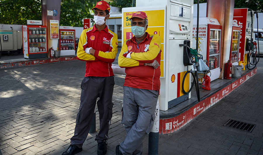 Employees wearing facemasks wait for customers at a gas station in Rawalpindi on May 31, 2020. (AFP)