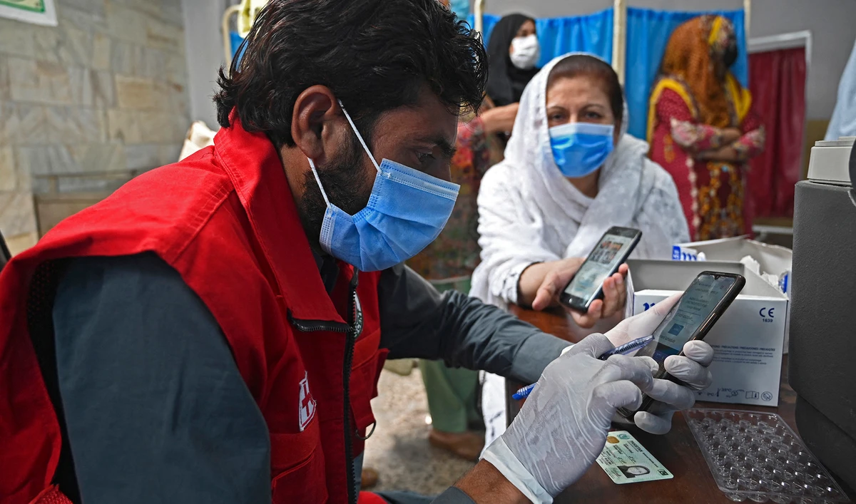 A health worker tracks the Covid-19 coronavirus vaccine registration code of a woman on his phone at the Red Crescent vaccination centre in Rawalpindi on May 24, 2021. (AFP/File)