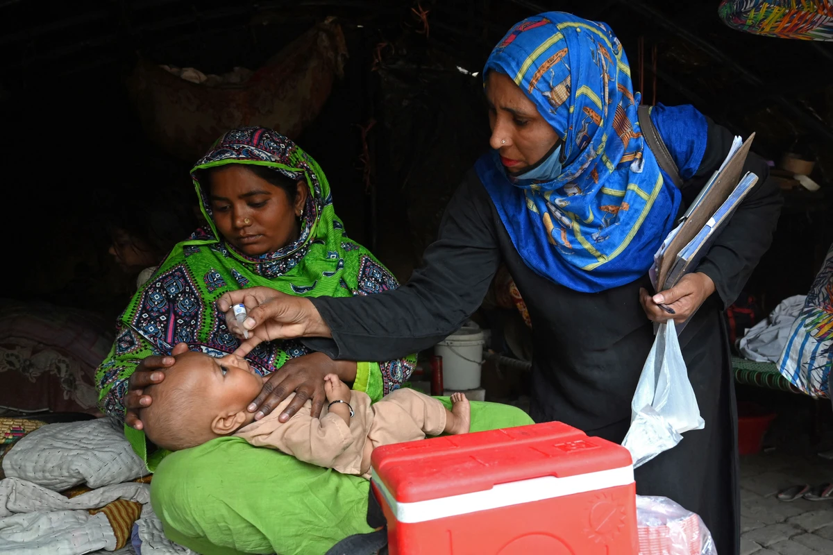 A health worker administers polio vaccine drops to a child during a polio vaccination door-to-door campaign at a slum area in Lahore on March 29, 2021. (AFP)