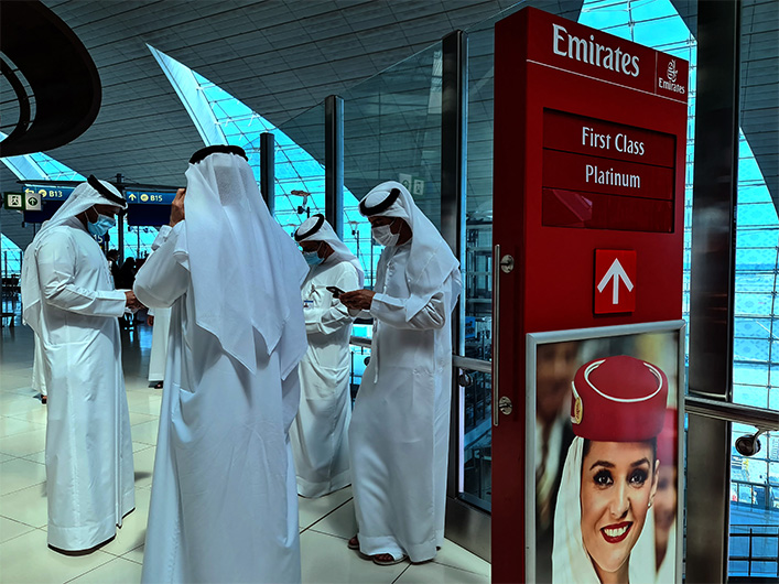 Employees and passengers browse their phones at the terminal at the Dubai international airport, on March 7, 2021. (AFP)