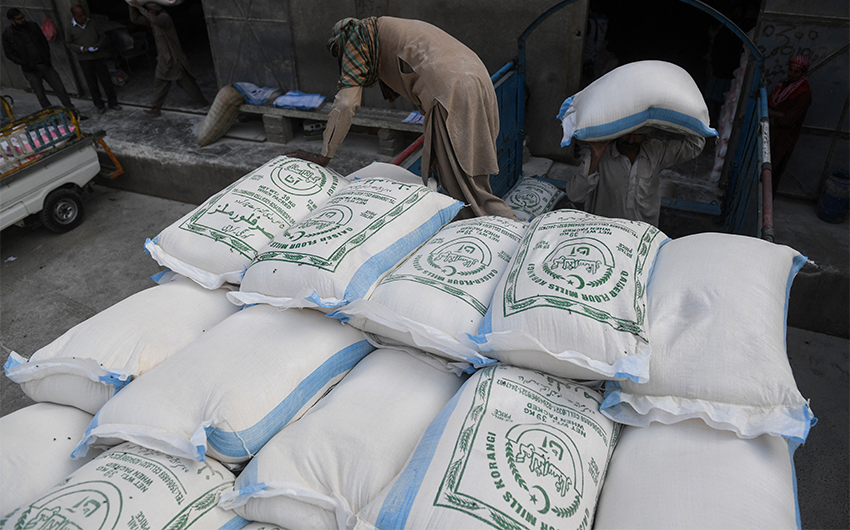 Labourers load sacks of wheat flour at a market in Karachi, Pakistan, on January 20, 2020. (AFP/File)