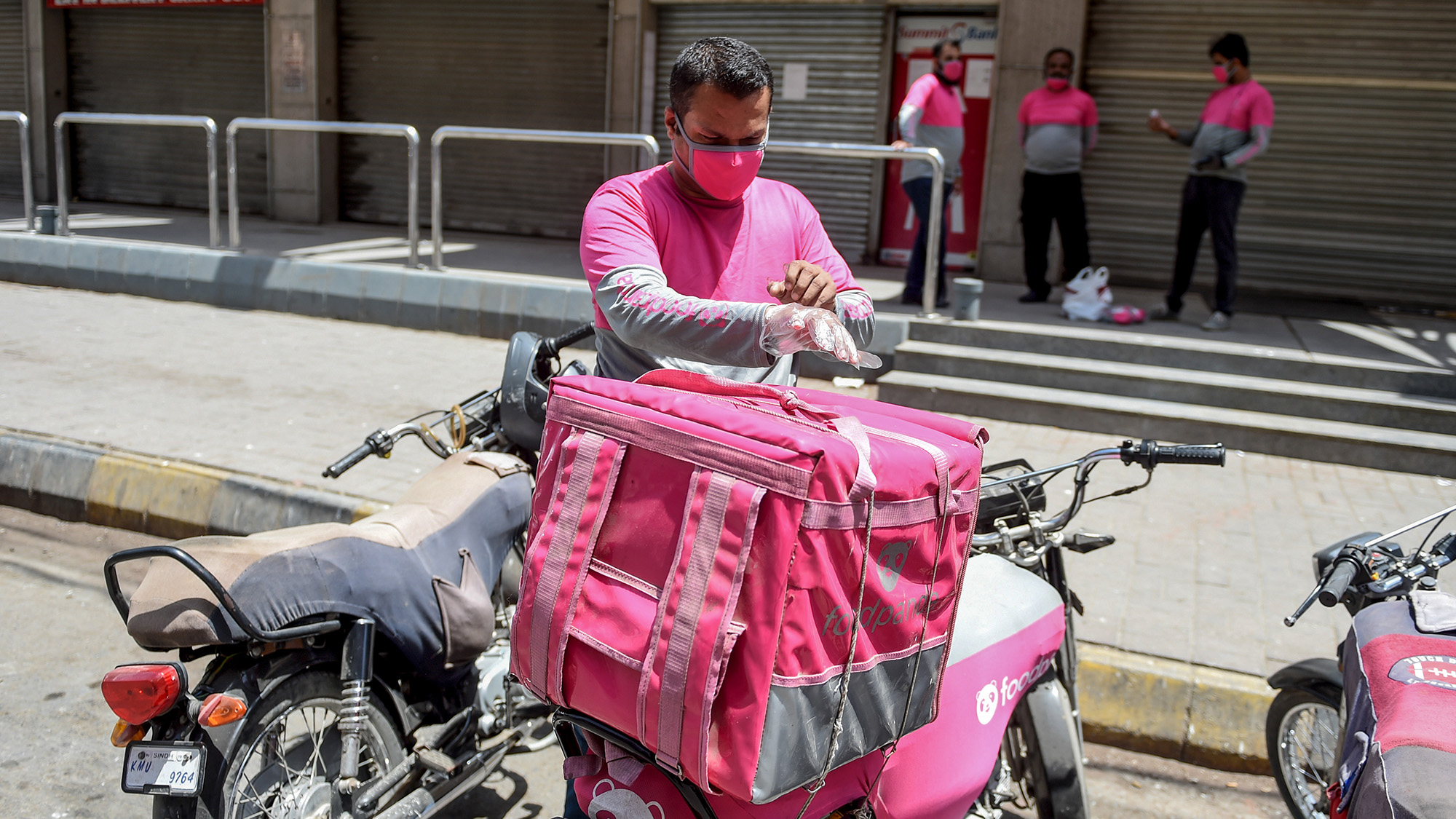A FoodPanda food delivery employee puts gloves on before delivering food in Karachi on April 18, 2020. (AFP/File)