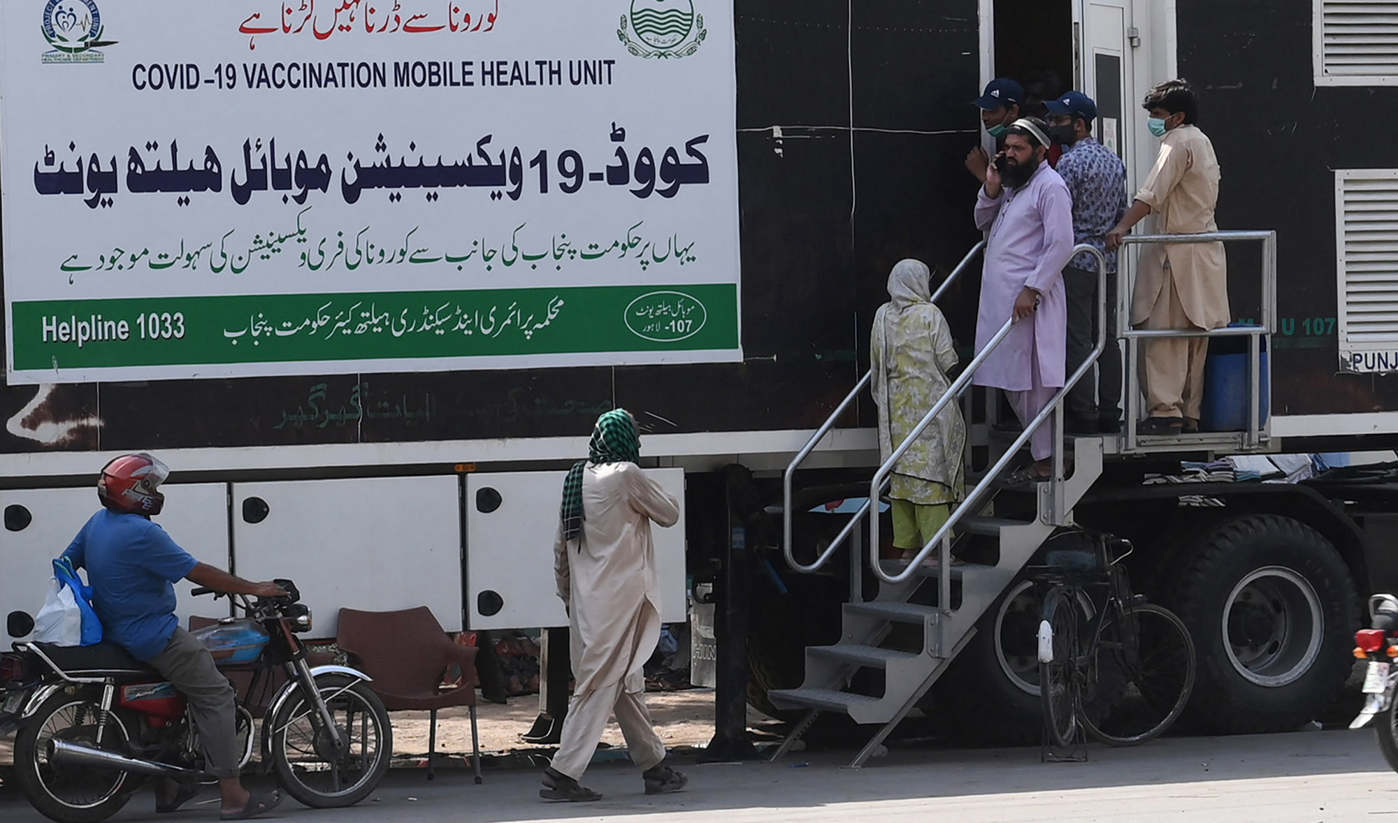 People wait for their turn to get a dose of a vaccine against the Covid-19 coronavirus outside a mobile vaccination health unit in Lahore on July 7, 2021. (AFP)