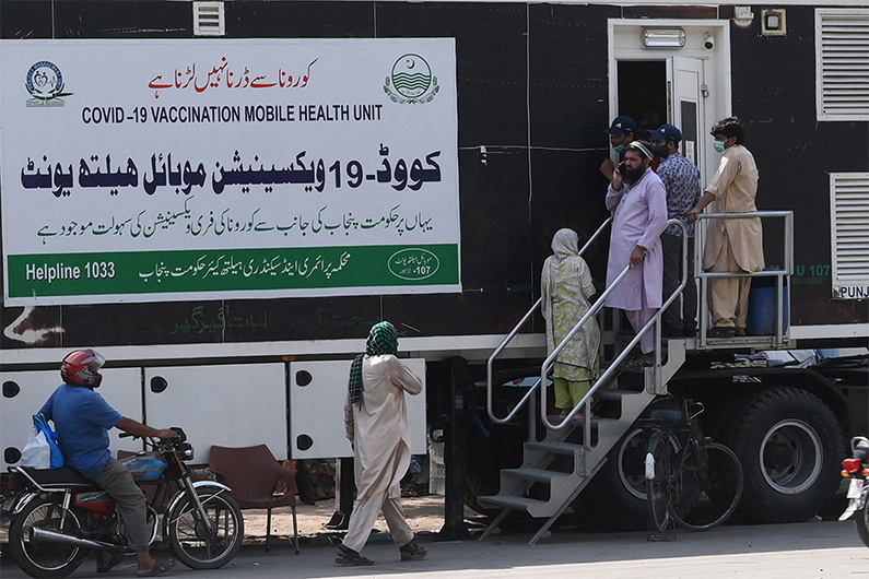 People wait for their turn to get a dose of a vaccine against the Covid-19 coronavirus outside a mobile vaccination health unit in Lahore on July 7, 2021. (AFP)