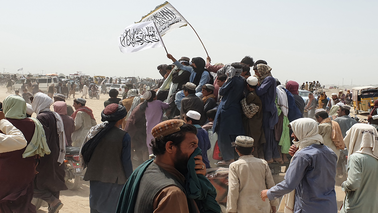 People wave Taliban flags as they drive through the Pakistani border town of Chaman on July 14, 2021, after the Taliban claimed they had captured the Afghan side of the border crossing of Spin Boldak along the frontier with Pakistan. (AFP)
