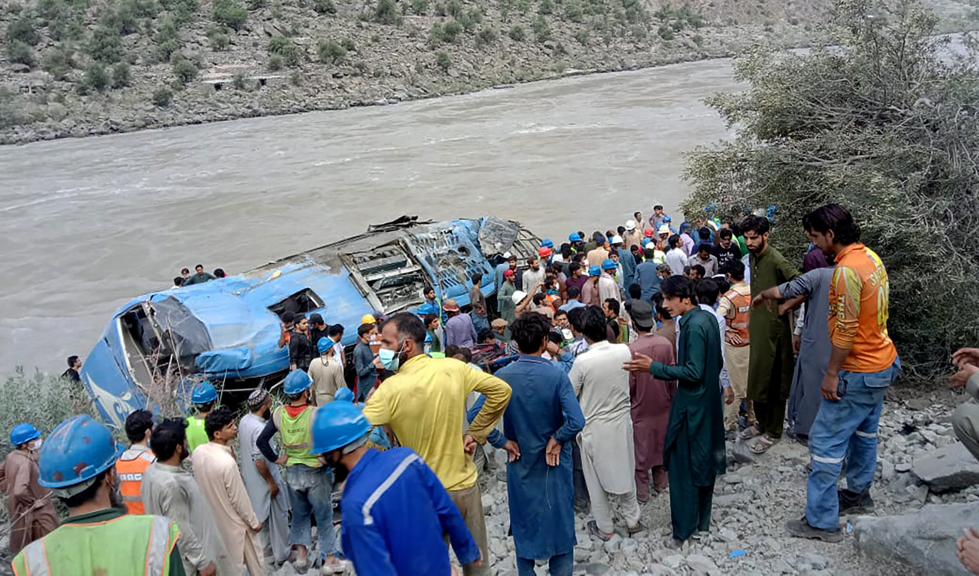 Rescue workers and onlookers gather around a wreck after a bus plunged into a ravine following a bomb explosion in Kohistan district of Khyber Pakhtunkhwa province on July 14, 2021. (AFP)