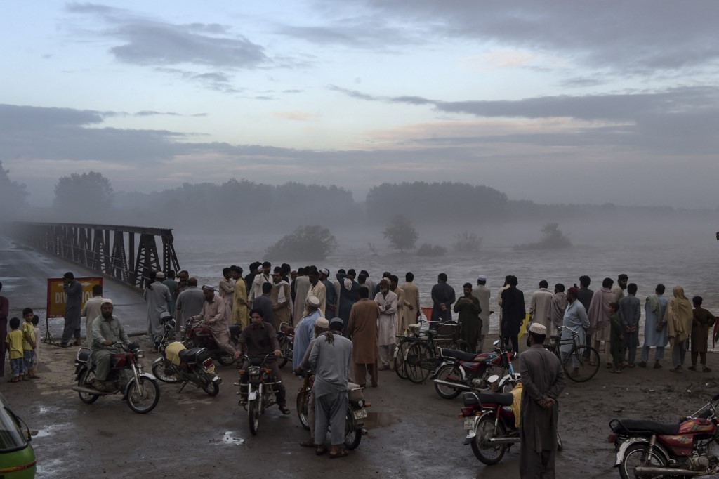 In this file photo, local residents gather to watch the swallen Charsadda river flow under a bridge following heavy monsoon rainfalls, on the outskirts of Peshawar on September 2, 2020. (AFP/File)