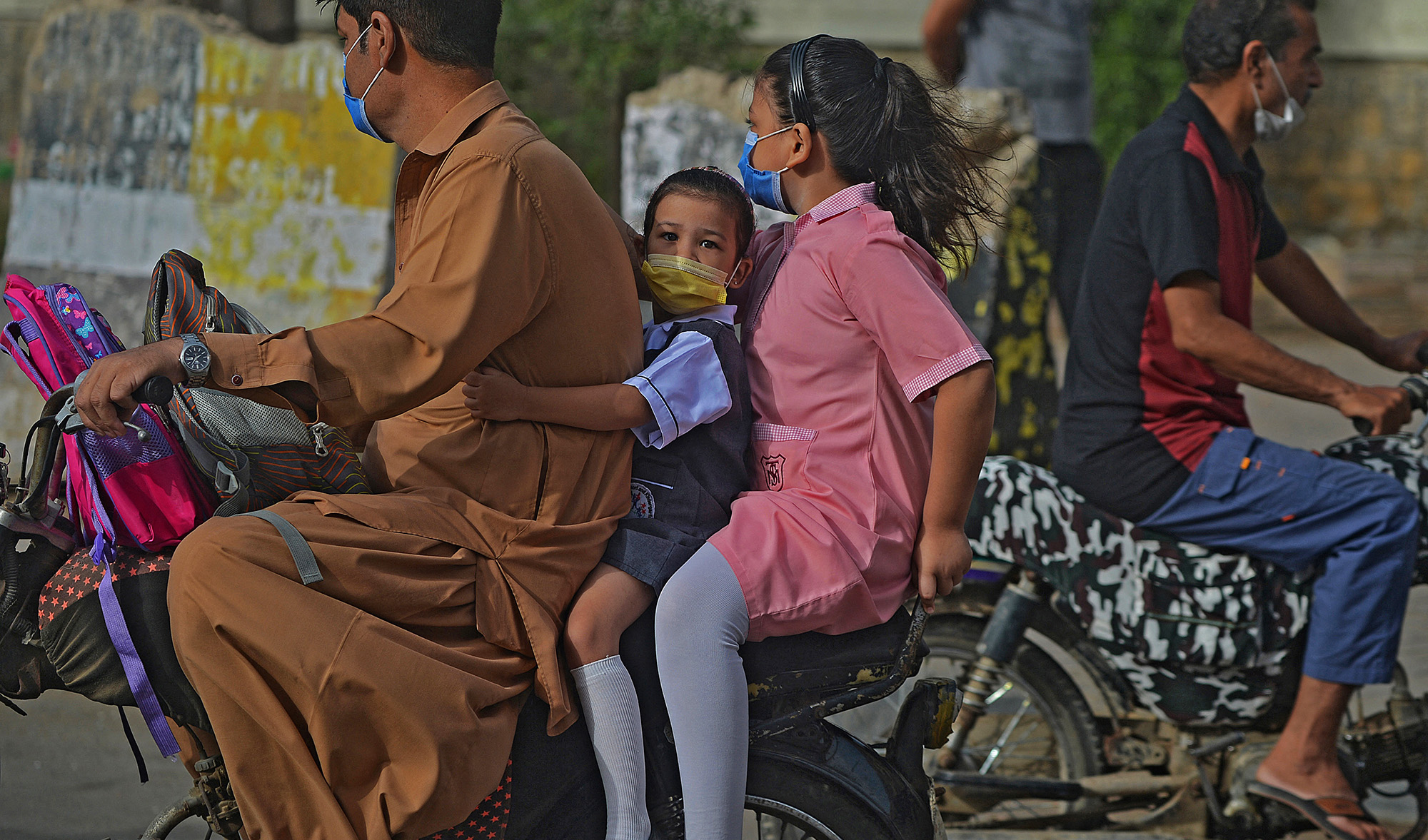 Children riding as a pillion on a motorcycle on their way to a school in Karachi on June 21, 2021. (AFP/File)