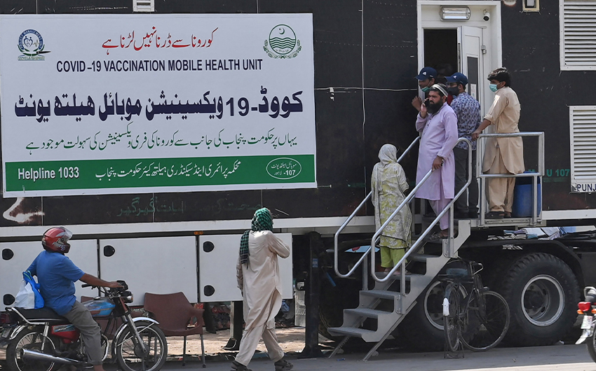 People wait for their turn to get a dose of a vaccine against the coronavirus outside a mobile vaccination health unit in Lahore, Pakistan, on July 7, 2021. (AFP)