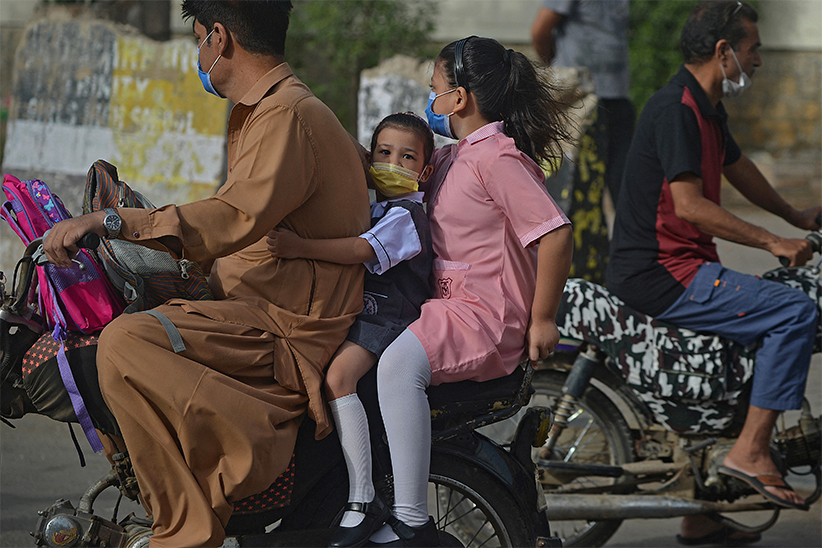 Children riding as a pillion on a motorcycle on their way to a school in Karachi on June 21, 2021. (AFP)