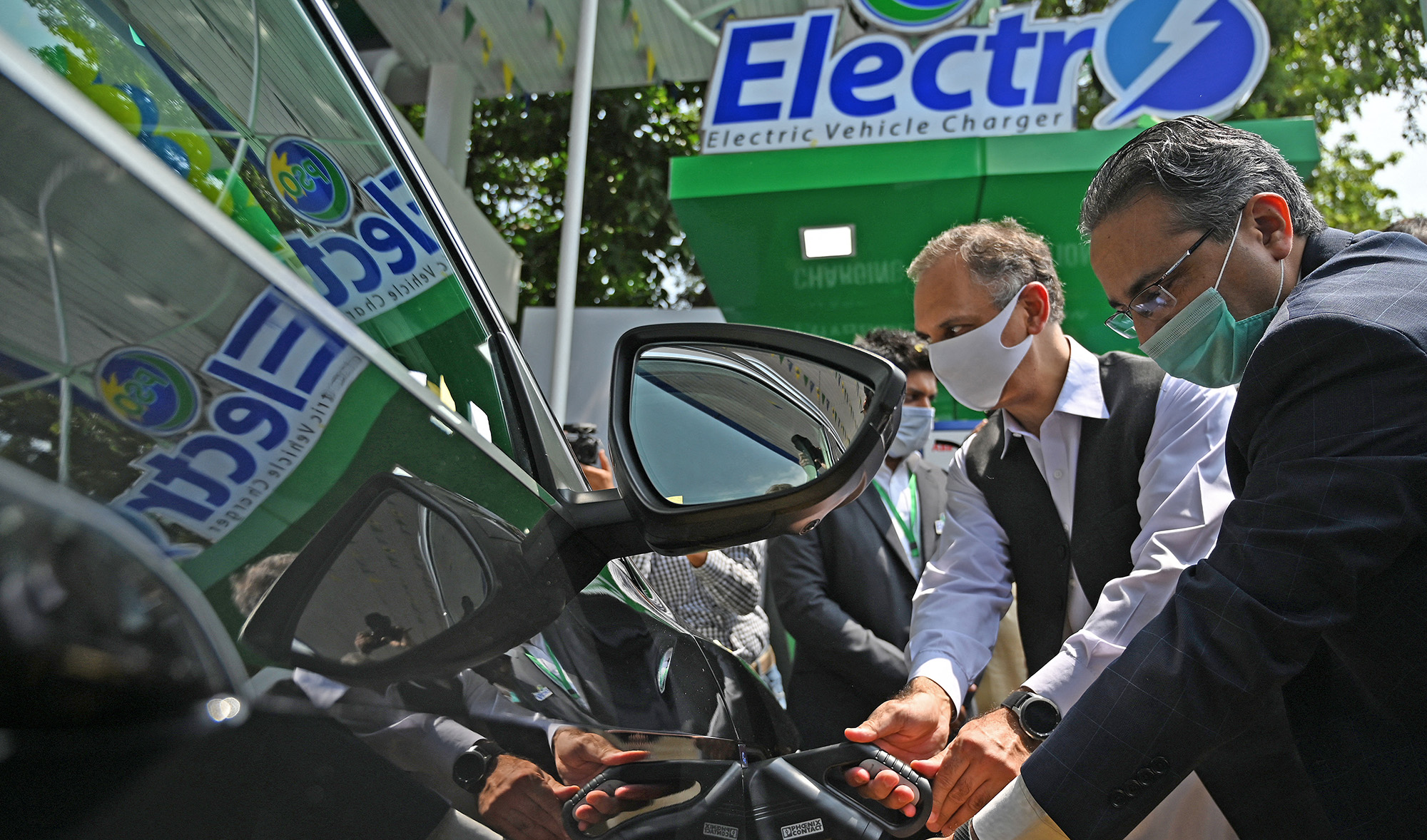 Pakistan's energy minister Omar Ayub Khan and Prime Minister's advisor on Petroleum Nadeem Babar charge an electric car during the inauguration ceremony of country's first electric vehicle charging station, in Islamabad on July 29, 2020. (AFP/File)