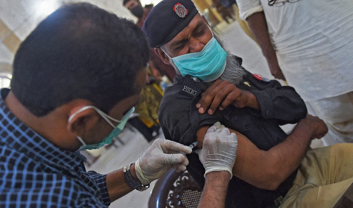 A health worker incoluates a policeman with a dose of the Sinopharm vaccine against the Covid-19 coronavirus at a vaccination center in Karachi on May 17, 2021. (AFP/File)