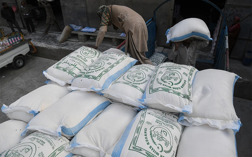 Labourers load sacks of wheat flour at a market in Karachi, Pakistan, on January 20, 2020. (AFP/File)