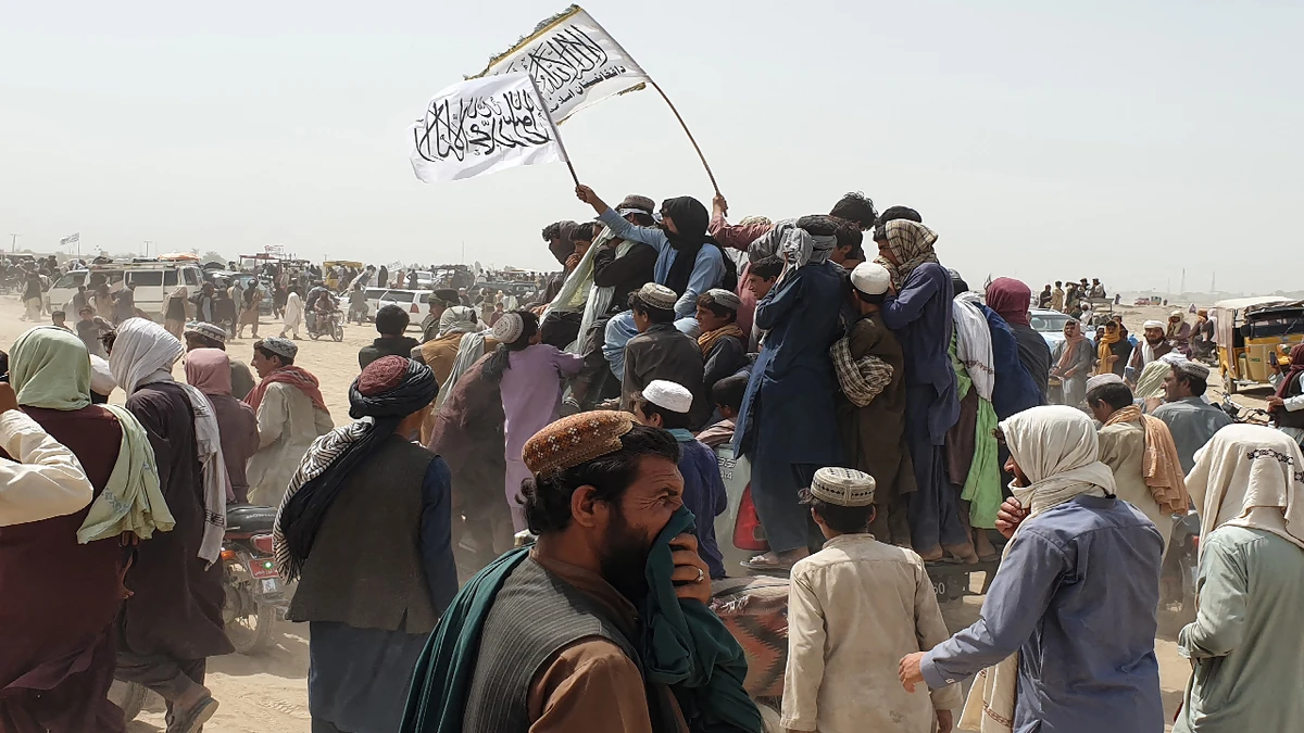 People wave Taliban flags as they drive through the Pakistani border town of Chaman on July 14, 2021, after the Taliban claimed they had captured the Afghan side of the border crossing of Spin Boldak along the frontier with Pakistan. (AFP)